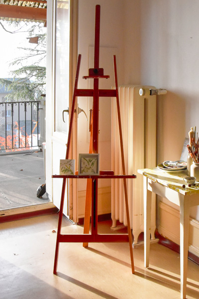 Staffelei mit Kunstwerken, Ateliertisch mit Pinseln und Ausblick auf die Terrasse - Regula Schenk