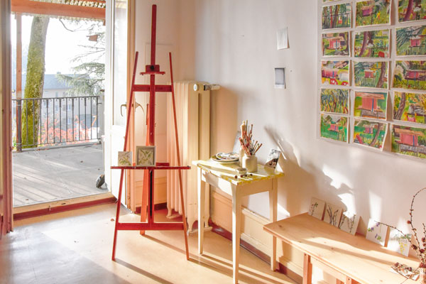 Staffelei mit Kunstwerken, Ateliertisch mit Pinseln und Ausblick auf die Terrasse - Regula Schenk